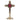 A polished brass cross-shaped reliquary with a round relic compartment and an ornate base. 
Front view